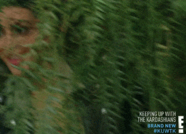 A person with long, dark hair emerges from behind hanging green foliage, revealing their face slowly. Text on the bottom right reads, "KEEPING UP WITH THE KARDASHIANS BRAND NEW #KUWTK" followed by the E! Network logo. - Choice Hacking Academy A person with long, dark hair emerges from behind hanging green foliage, revealing their face slowly. Text on the bottom right reads, "KEEPING UP WITH THE KARDASHIANS BRAND NEW #KUWTK" followed by the E! Network logo.
