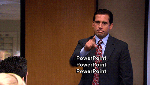A man in a suit stands in an office setting, pointing his finger forward with a serious expression. The text "PowerPoint. PowerPoint. PowerPoint." appears over the image, suggesting he is emphasizing or instructing something related to PowerPoint presentations.